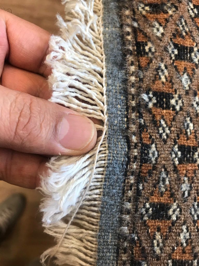 Frange consumate di un tappeto annodato a mano in fase di restauro nel laboratorio Art Tappeti a Milano