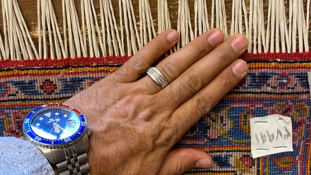 Artigiano di Art Tappeti ripara a mano le frange di un tappeto persiano a Milano