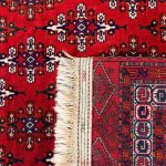 Dettaglio del tappeto Turcaman persiano: retro con nodi a mano, frange in lana e bordure geometriche